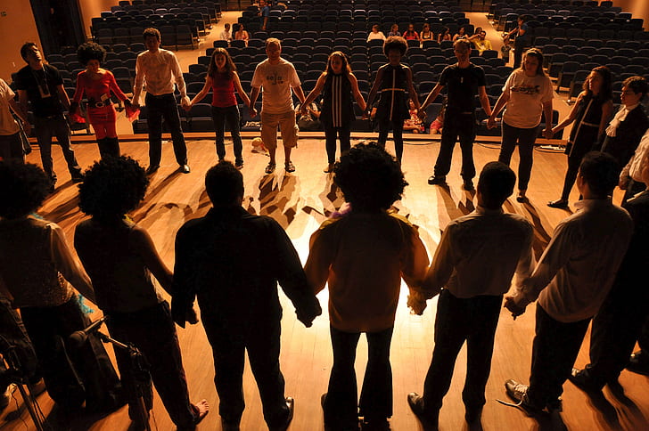 A diverse group holding hands in a circle during an improv experience